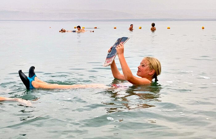 Child reading a newspaper while floating in the Dead Sea - on a Jordan family holiday