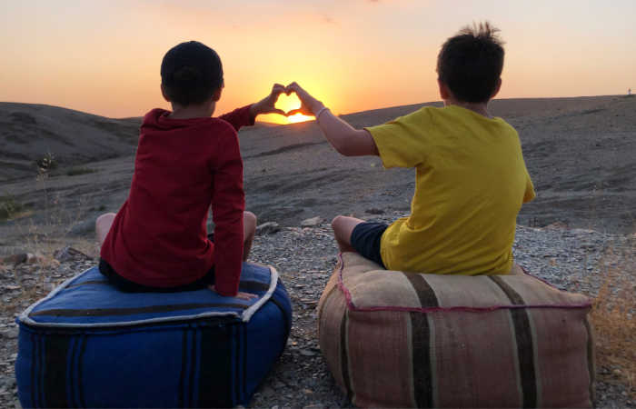Kids on a Morocco family holiday watching the sunset in the desert