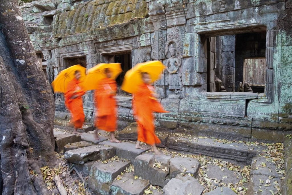 Monks in bright orange robes at Angkor Wat on Cambodia family holidays