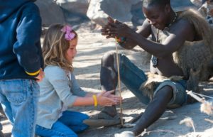 Young girl learning to make fire on a Tanzania family safari