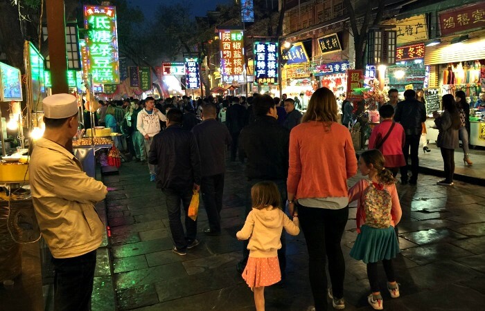 A bustling street scene in China with a mum and two children exploring on a long haul family holiday