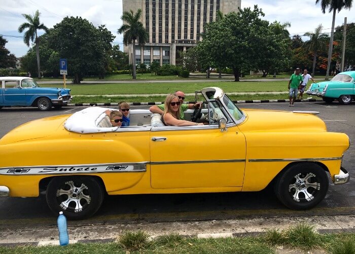 Long haul family travel - family in a hired classic car in Havana