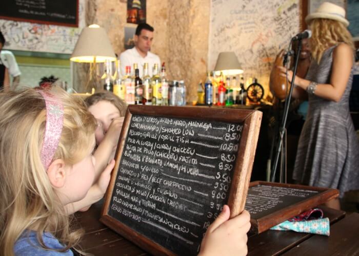 Long haul family holiday - two girls look at the menu in a cool Cuban bar