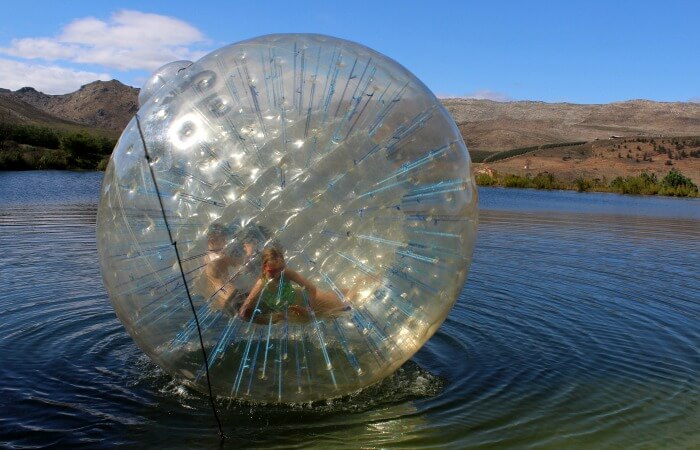 South Africa for families itinerary - teenagers zorbing on lake in Western Cape