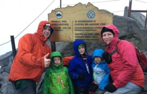Family climbing Mount Kinabalu reaching the summit in rain and cloud