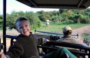 A smiling 4 year old on safari on a family safari holiday - South Africa family holiday