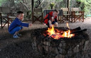 Teeneager and toddler enjoying toasting marshmallows on fire pit - South Africa for families