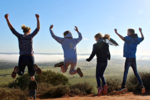 South Africa for families trip - family jumping up in the air on hill top