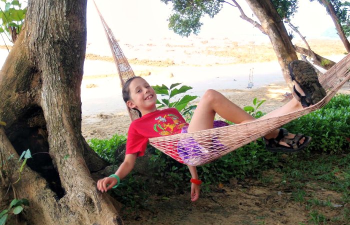 Family Christmas breaks in Thailand - young girls playing in a hammock beside the beach in Thailand