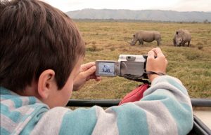 Child on a family safari holiday taking a photo of rhino