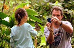 Young girl with butterfly on her arm - Ecuador with kids itinerary - Mashpi Lodge