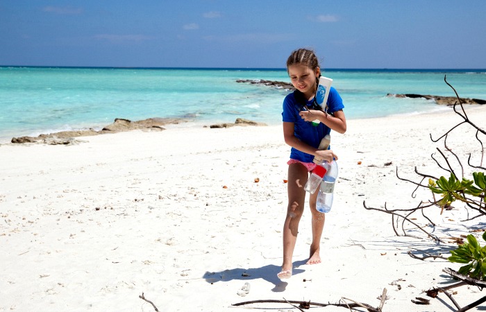Conscious traveller blog - child collecting up plastic on the beach