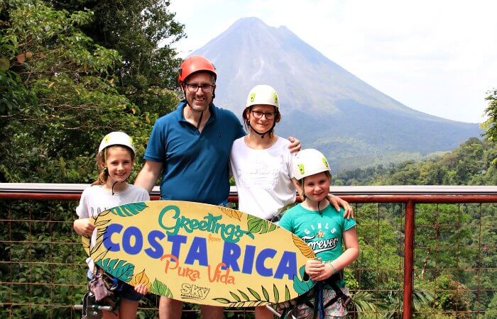 Photo of family in Arena holding a sign saying 'Greetings from Costa Rica'
