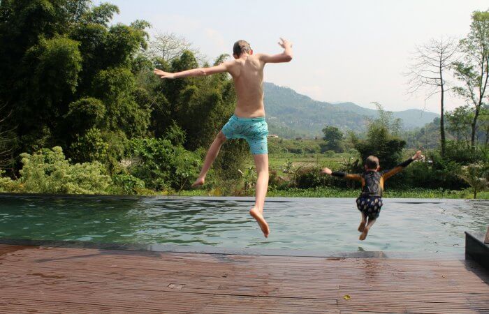 Nepal with kids holiday - two boys jumping into a swimming pool on Easter Family holidays