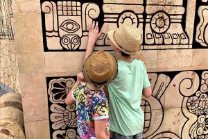 Two boys looking at Mayan carvings - Mexico with kids holiday itinerary
