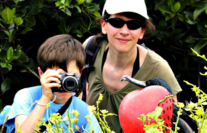 Child and parent photographing red frigate bird