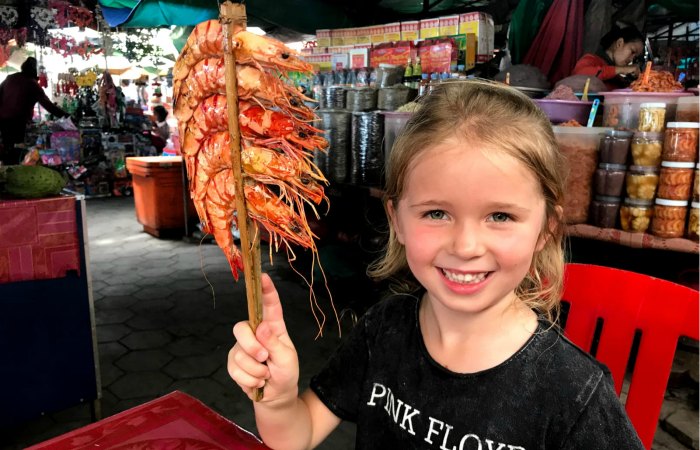 Child with giant prawns on a stick - family adventure holiday in Cambodia