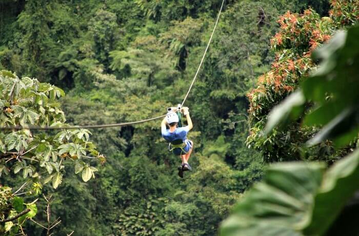 Teenager on holiday zip-lining in Costa Rica above the rainforest