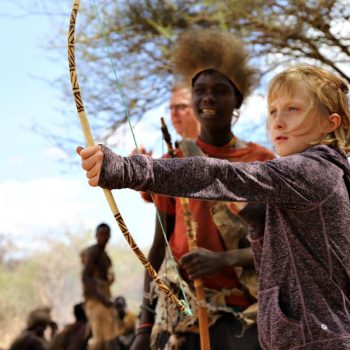 Kids learning to use a traditional bow and arrow on a Tanzania with kids holiday