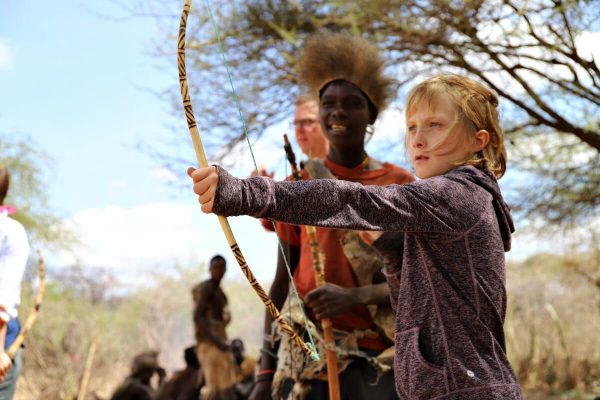 Kids learning to use a traditional bow and arrow on a Tanzania with kids holiday