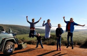 Sundowners on safari in South Africa - family jumping with stunning scenery in background
