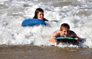 Teenagers body boarding on South Africa with children family holiday