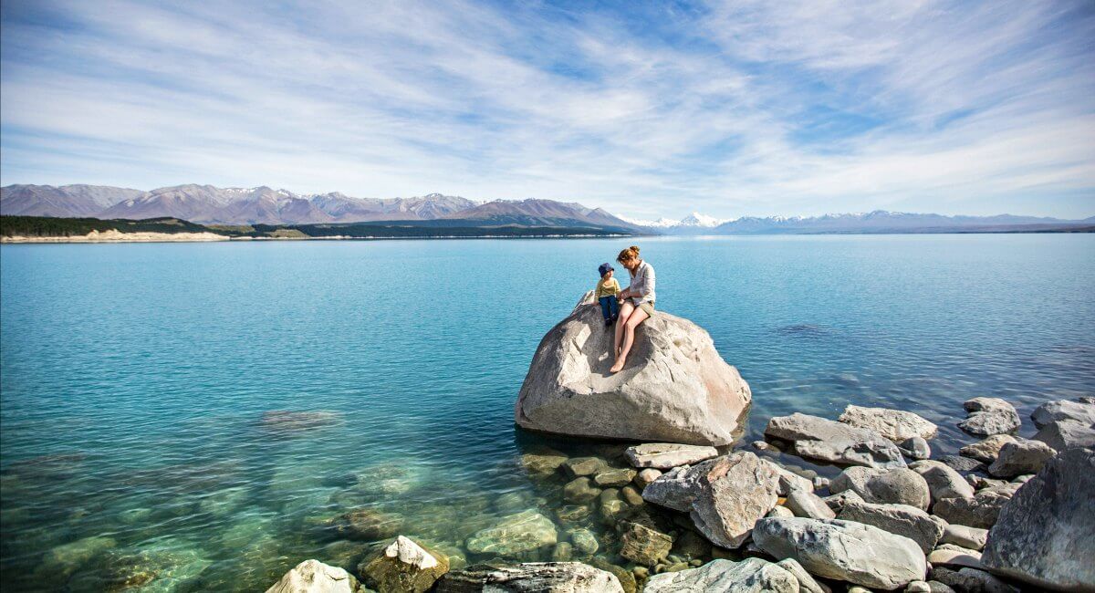 New Zealand in pictures - mother and child on boulder, Lake Pukaki with views of Mount Cook