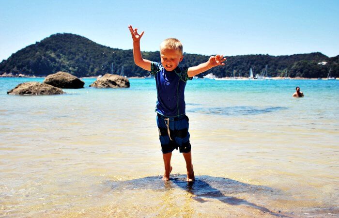 Boy playing in the water at Abel Tasman on New Zealand family holiday
