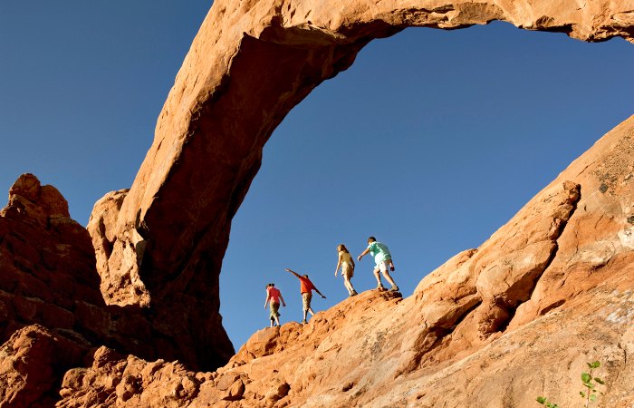Family walking along a rock ridge in Arches National Park