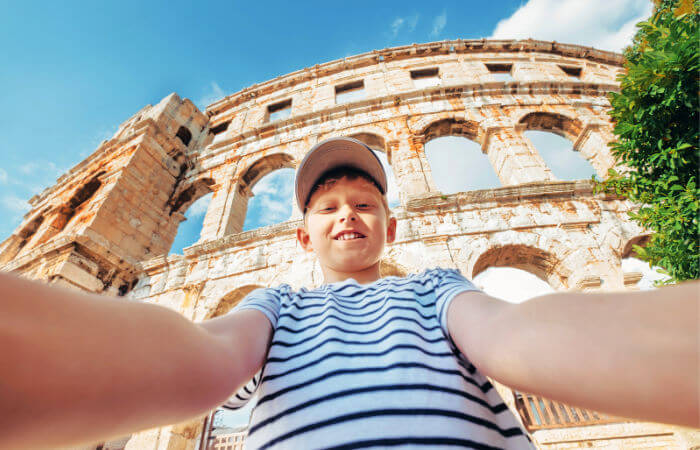 Boy taking a selfie in front of Pula's Roman ruins on a Croatia family holiday