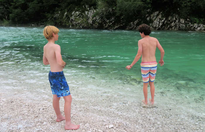 Two boys taking dip in the Soca River on a family holiday in Slovenia