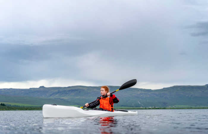 Iceland family holidays - girl paddling kayak on scenic Laugarvatn lake.