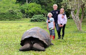 Kids with giant tortoise in the Galapagos - family summer holidays