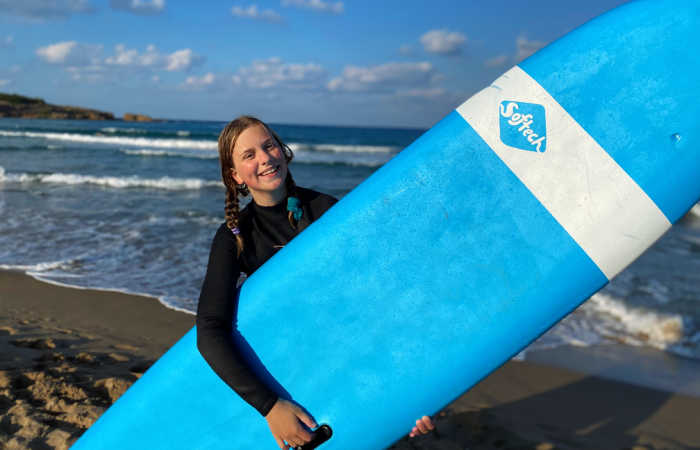 Girl with blue surf board in Crete - Easter, Summer and Autumn half-term holidays