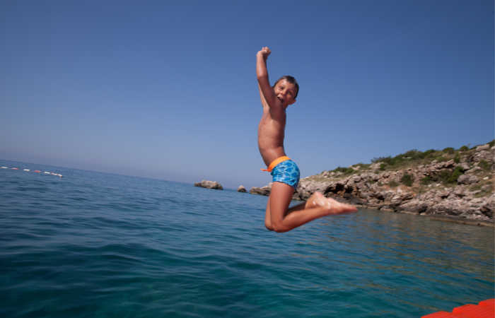Child jumping into the sea from a hotel deck on a Montenegro family holiday