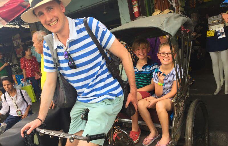 Dad pedals the tuk tuk for two children in Thailand