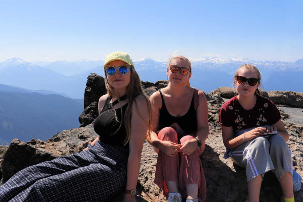 Family in Rockies - three young women sitting in front of stunning mountain backdrop.