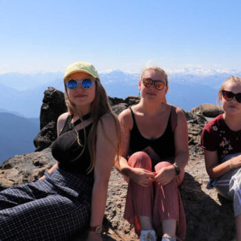 Family in Rockies - three young women sitting in front of stunning mountain backdrop.