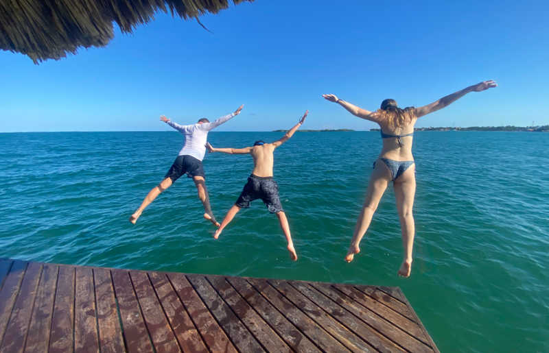 Family jumping into azure waters in Belize on February half term holiday