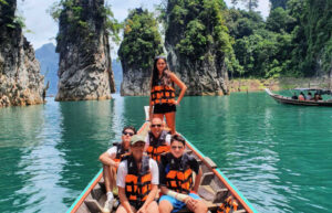 Teenagers exploring Southern Thailand on a boat excursion with karst scenery behind them