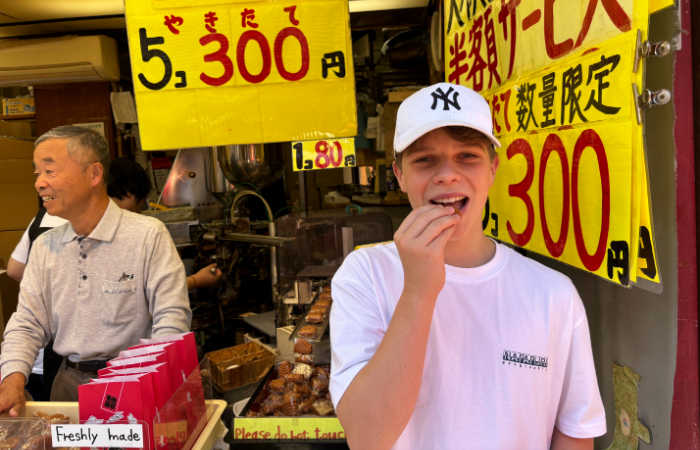 Youngster trying Japanese snacks in Tokyo on family summer holiday