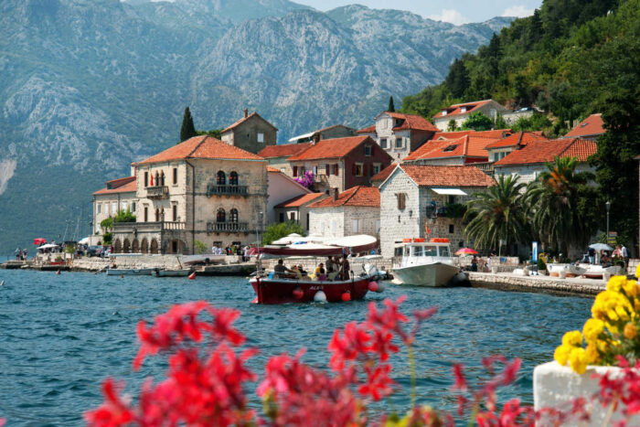 Where to stay in Montenegro - coastal photo with boat and red flowers