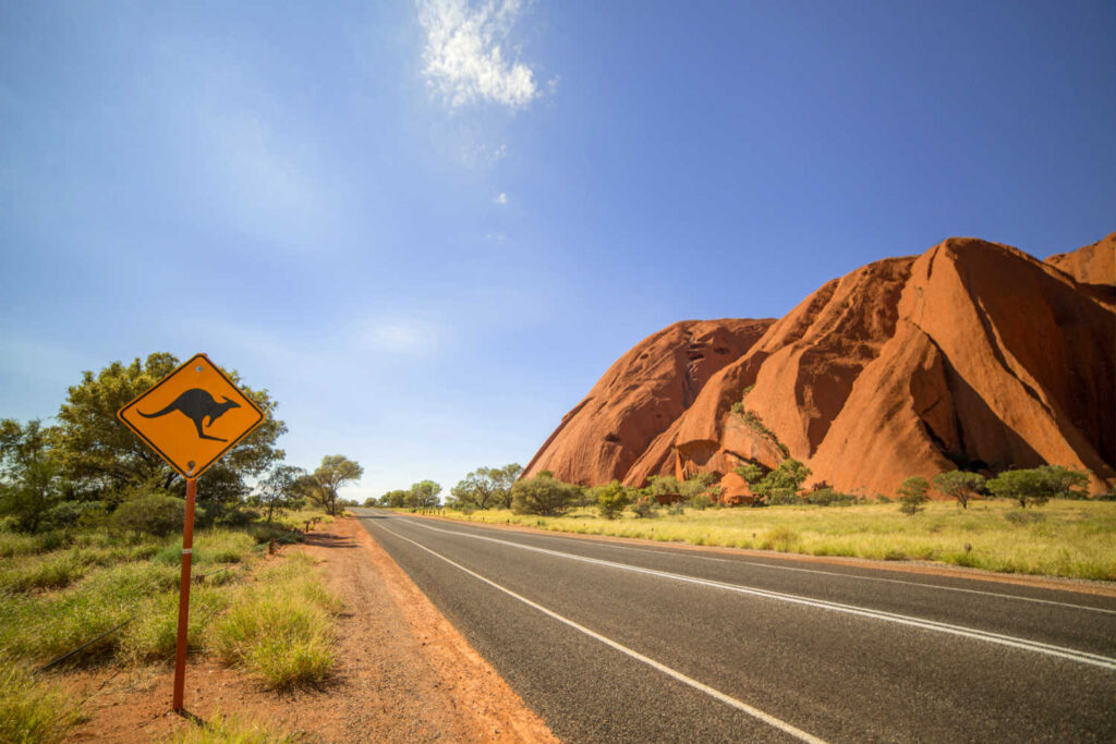 Landscape with sandstone monolith, blue sky and kangaroo sign, on Australia family holiday