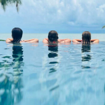 Kids in an infinity pool looking over the blue ocean, family bucket list holidays