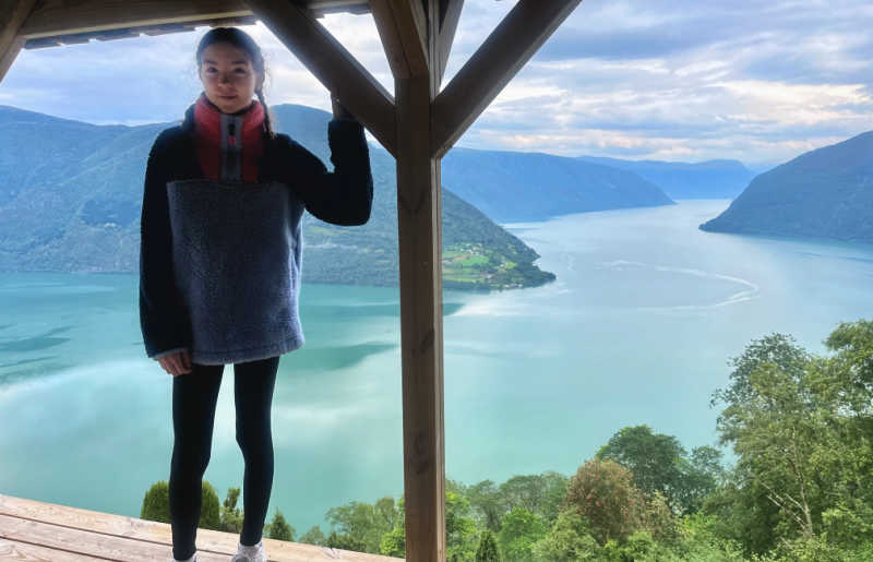 Norway fjord view, with girl standing in the foreground and a huge fjord vista behind her