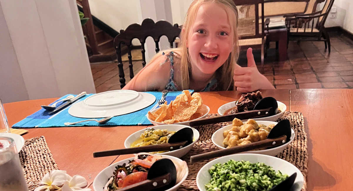 Girl making thumbs up sign with delicious Sri Lankan dishes in front of her on the table