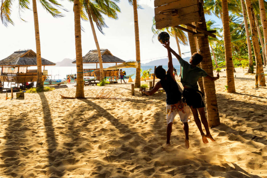 Kids playing basket ball on beach, family travel in Asia