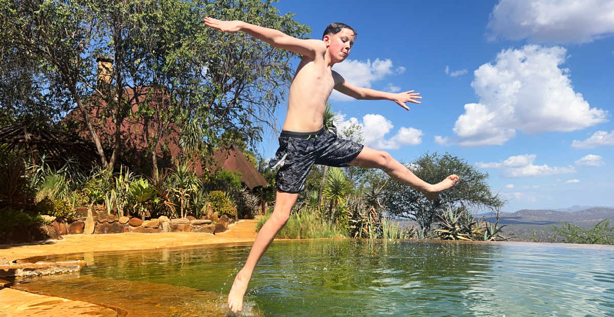 Boy jumping into pool at Laikipia lodge, Kenya