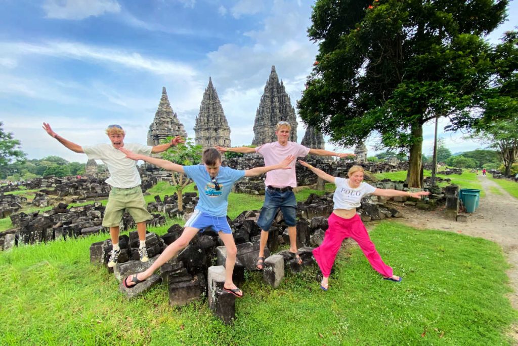 Gap year holiday meet-up in Indonesia, siblings and friend jumping in front of ancient temple