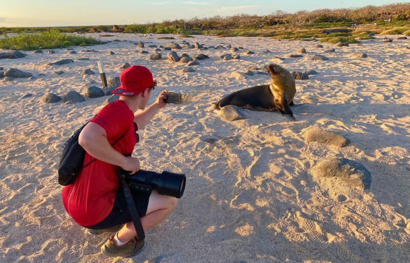 Teenager taking close up photo of seals in Galapagos - Easter family holidays in Ecuador